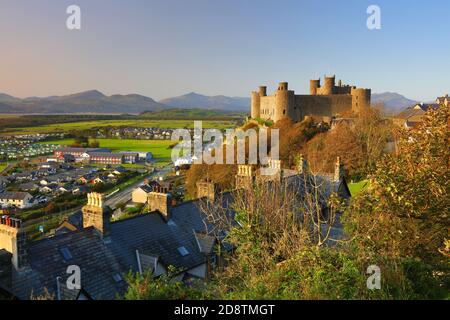 Château de Harlech en fin de soirée lumière du soleil et ciel bleu avec des montagnes au loin, Snowdonia, nord du pays de Galles, Royaume-Uni. Banque D'Images