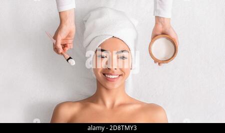 Soin du visage. Cosmétologue appliquant un masque en argile sur le visage de la femme asiatique au spa Banque D'Images