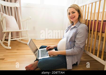 Belle jeune femme enceinte avec ordinateur portable Banque D'Images