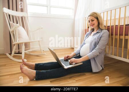 Belle jeune femme enceinte avec ordinateur portable Banque D'Images
