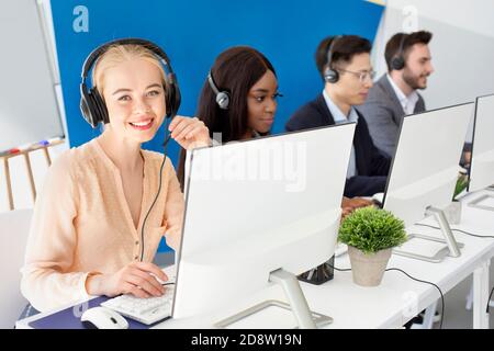 Une équipe multinationale d'opérateurs de centre d'appels s'adressant aux clients en ligne au bureau moderne Banque D'Images