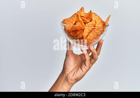 Main de l'homme hispanique tenant un bol avec des pommes de terre nachos mexicaines sur fond blanc isolé. Banque D'Images