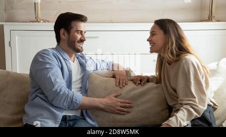 Agréable couple de la famille millénaire ayant une conversation gaie dans le salon Banque D'Images