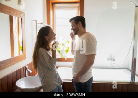 Couple marié millénaire souriant nettoyant les dents dans la salle de bains moderne Banque D'Images