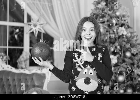 Le rouge est mon préféré. Décor d'attributs de Noël. Petite fille près de l'arbre de Noël. Enfant célébrer Noël à la maison. Traditions d'hiver. Adorable gamin excité porter le chandail de noël. Boutique cadeaux concept. Banque D'Images