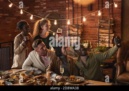 Groupe multiethnique d'adultes joyeux prenant des photos de selfie pendant profitez de la fête grâce à l'éclairage extérieur Banque D'Images