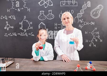 Écolière intelligente et professeur de chimie dans la tenue de Whitecavoine tubes Banque D'Images