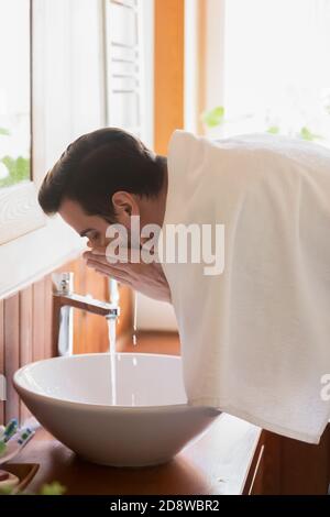 Homme millénaire se lavant le visage dans un lavabo moderne après le rasage Banque D'Images