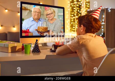 Grand-parents souriants avec gâteau d'anniversaire félicitant petit-fils avec anniversaire en ligne Banque D'Images