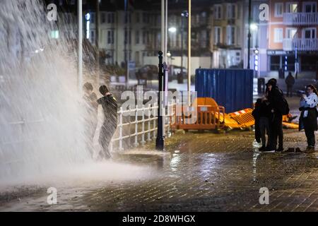 Aberystwyth, Ceredigion, pays de Galles, Royaume-Uni. 1er novembre 2020 Royaume-Uni Météo : un vent fort combiné à une marée haute provoque d'énormes vagues qui se brisent le long de la promenade d'Aberystwyth, alors que deux personnes pendent sur les rampes et postent tout en se trempant. © Ian Jones/Alamy Live News Banque D'Images