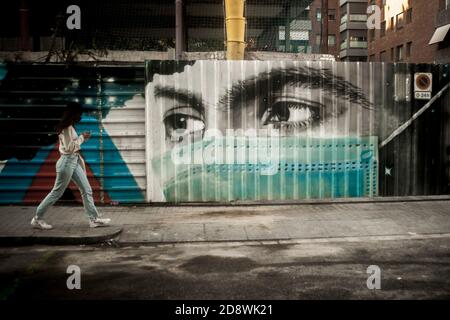 Barcelone, Catalogne, Espagne. 1 novembre 2020, Barcelone, Catalogne, Espagne: À Barcelone, une femme passe devant une clôture décorée d'un masque chirurgical graffiti. Malgré les mesures prises ces dernières semaines, le coronavirus continue de se propager à travers l'Espagne et les nouveaux cas de Covid-19 ont atteint un nombre record. Jordi Boixareu/Alamy Live News Banque D'Images