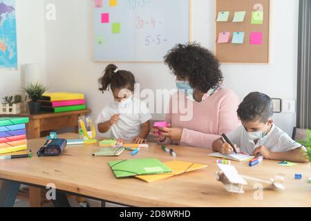 Enseignant aidant les enfants d'âge préscolaire pendant l'éclosion du coronavirus - Soft concentrez-vous sur le visage du garçon Banque D'Images