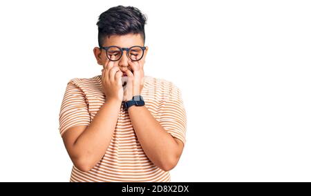 Petit garçon enfant portant des vêtements décontractés et des lunettes frottant les yeux pour la fatigue et les maux de tête, l'expression endormie et fatiguée. Problème de vision Banque D'Images