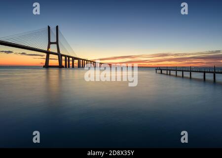 Arrière-plan avec lever de soleil coloré sur le pont de Lisbonne. Le pont Vasco da Gama est un point de repère et l'un des plus longs ponts du monde. réseau local urbain Banque D'Images