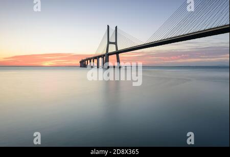 Arrière-plan avec lever de soleil coloré sur le pont de Lisbonne. Le pont Vasco da Gama est un point de repère et l'un des plus longs ponts du monde. réseau local urbain Banque D'Images