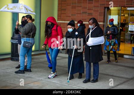 Brooklyn, NY - 1er novembre 2020. Les électeurs du quartier Midwood de Brooklyn se sont mis en ligne sous une légère pluie dans un bureau de vote du Brooklyn College pour voter le dernier jour de vote par anticipation lors de l'élection présidentielle de 2020 à New York. La femme du centre a voté très tôt parce qu'elle n'avait pas confiance dans l'envoi d'un bulletin de vote par courrier. Banque D'Images