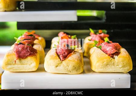 beaucoup de mini sandwiches avec du jambon, des olives, de la laitue servis sur un plateau blanc Banque D'Images