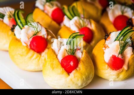 beaucoup de mini sandwiches avec des tranches de crevettes, de pastèque et de concombre servis sur un tableau blanc Banque D'Images