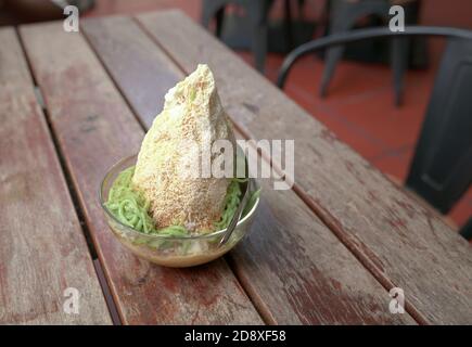 Cendol, glace douce rasée avec gelée de farine de riz verte servie dans un bol, sur une table en bois Banque D'Images