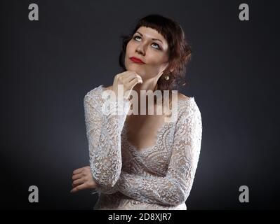 Photo de la femme rêveuse en robe à travers le décor sur fond sombre Banque D'Images