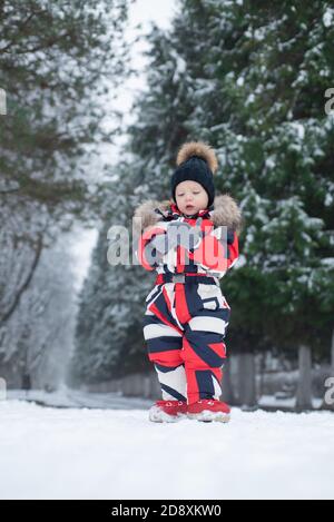 Les enfants marchent à l'extérieur et aiment marcher. Hiver. Mignon petit garçon. Enfant dans les vêtements d'hiver dans le parc avec de la neige. Enfant en chapeau d'hiver. Parc enneigé. Banque D'Images