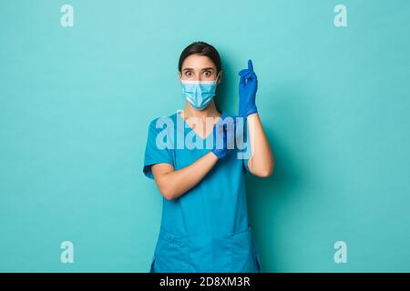 Covid-19, concept de pandémie et de médecine. Surpris belle femme dans le masque médical et les croûtes, mettre des gants et regardant auto-assuré, se préparer Banque D'Images