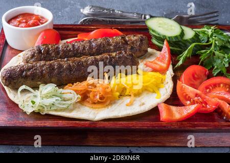 Un Kebab sur une pita avec des oignons marinés multicolores et un peu de sauce rouge Banque D'Images