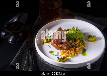 Un épaule d'agneau braisée avec une purée de brocoli et un peu de rôti haricots Banque D'Images