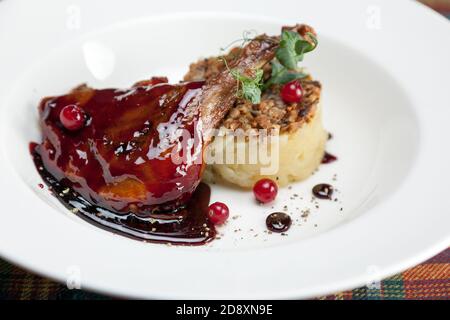 Cuisse de canard confit avec chanterelles, purée de pommes de terre et sauce à la framboise Banque D'Images