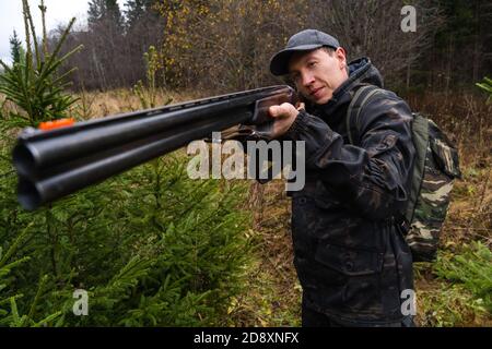 Chasseur visant un fusil de chasse dans une forêt Banque D'Images