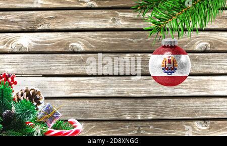 Concept du nouvel an et de Noël, sur fond de bois, branches d'arbres de Noël et jouet de Noël avec le drapeau de la Polynésie française. Banque D'Images