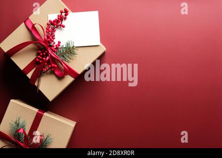 Cadeaux de Noël de luxe papier kraft emballé et carte de vœux vierge sur fond rouge marsala. Flat lay, vue de dessus, espace de copie. Banque D'Images