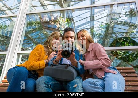 Groupe d'amis regardant des photos prises avec un réflexe caméra dans un parc Banque D'Images