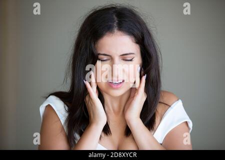 Jeune femme avec des mains de mal de dents sur les joues Banque D'Images