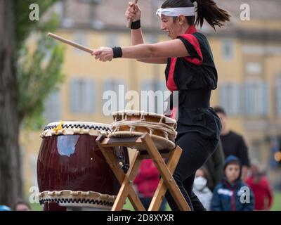 Fille jouant des tambours de la tradition musicale japonaise lors d'un événement public en plein air. Banque D'Images