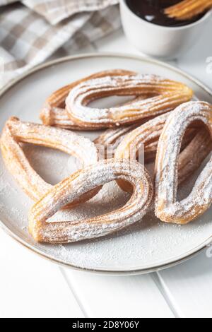 Délicieux churros frits avec sucre en poudre sur l'assiette. Banque D'Images