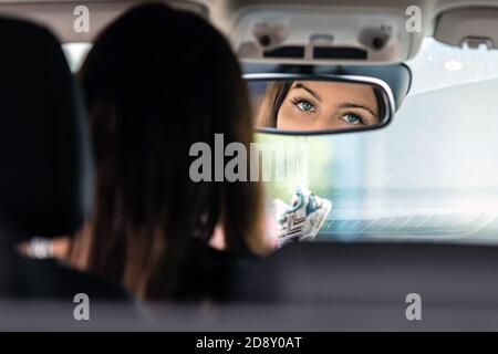 les beaux yeux de la jeune femme conducteur sont reflétés dans le rétroviseur Banque D'Images