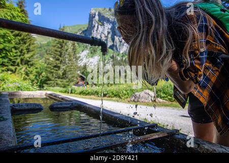 Portrait d'une jeune fille blonde qui lave son visage dans le lit de la rivière. Elle avec ses yeux fermés aime laver son visage humide du ruisseau à la main Banque D'Images