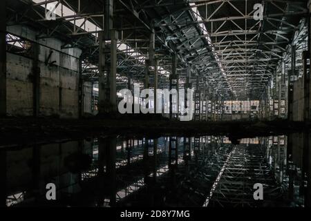 A l'intérieur d'un bâtiment industriel inondé et sale, abandonné, détruit avec réflexion de l'eau Banque D'Images