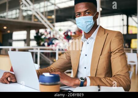 Portrait d'un homme d'affaires portant un masque travaillant sur un ordinateur portable à chaud Bureau en cabinet pendant une pandémie de santé Banque D'Images