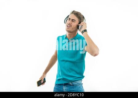 un homme séduisant qui écoute de la musique avec un casque et danse avec plaisir Banque D'Images