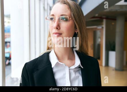Portrait d'une jeune femme d'affaires portant des lunettes debout dans un bureau moderne Pendant la pandémie de santé Banque D'Images