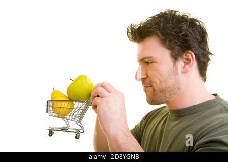 Un jeune homme pousse un petit chariot avec des fruits Banque D'Images