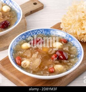 Gros plan de la soupe traditionnelle chinoise douce aux champignons blancs avec graines de lotus, dattes rouges (jujujube) et baies de carcajou (baie de goji, baie de gogyberry) sur le dos blanc Banque D'Images