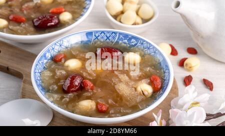Gros plan de la soupe traditionnelle chinoise douce aux champignons blancs avec graines de lotus, dattes rouges (jujujube) et baies de carcajou (baie de goji, baie de gogyberry) sur le dos blanc Banque D'Images