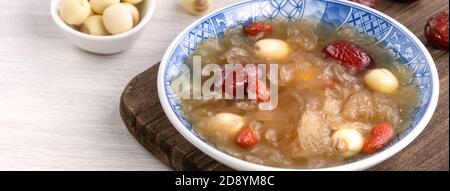 Gros plan de la soupe traditionnelle chinoise douce aux champignons blancs avec graines de lotus, dattes rouges (jujujube) et baies de carcajou (baie de goji, baie de gogyberry) sur le dos blanc Banque D'Images