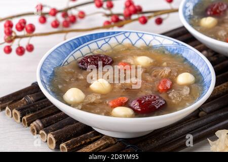 Gros plan de la soupe traditionnelle chinoise douce aux champignons blancs avec graines de lotus, dattes rouges (jujujube) et baies de carcajou (baie de goji, baie de gogyberry) sur le dos blanc Banque D'Images