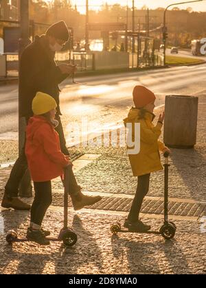 Père et deux filles avec masque traversent la rue À la station de métro Hradcanska avec des scooters pendant la période de quarantaine prévue À l'épidémie de COVID Banque D'Images