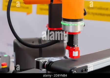 Prenez et placez le bras de préhension robotique manipulateur déplaçant les blocs de jouets rouges au salon de robot moderne, exposition - vue rapprochée. Fabrication, ingénierie Banque D'Images