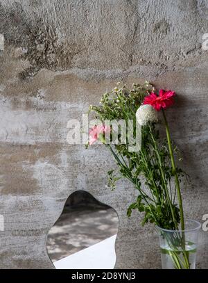 Fleurs et miroir sur la table avec un fond de mur de ciment avec de l'espace pour votre texte. Banque D'Images